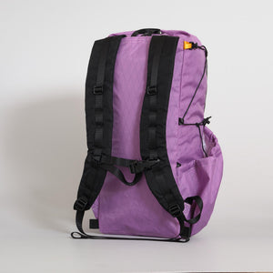 A purple (mulberry) backpack with black straps, buckles, and side compression cords, shown from the back against a light gray background. Made from X-Pac VX21 fabric in Australia.