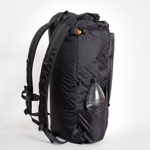 OrangeBrown backpack OB 36 from the side showing side pocket with stored water bottle and side compression cord, which is adjustable via a Line Loc 3.