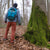 A cold February afternoon in a German forest. A hiker standing next to an old beech tree overgrown with moss.