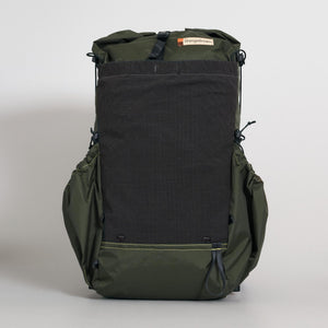 A dark green roll-top backpack with a front stretch mesh pocket, solid fabric side pockets, and a roll top closure. Handmade from X-Pac VX21 fabric in Australia. Photographed against a neutral light gray background.
