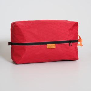 Red large packing cube with a black zipper made with X-Pac VX21 fabric on a light gray background