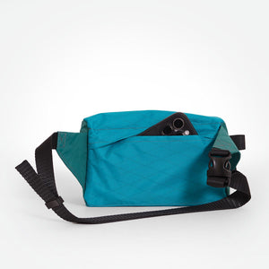 Teal and green waist bag with black strap made from X-Pac VX21 fabric and a hidden back pocket.