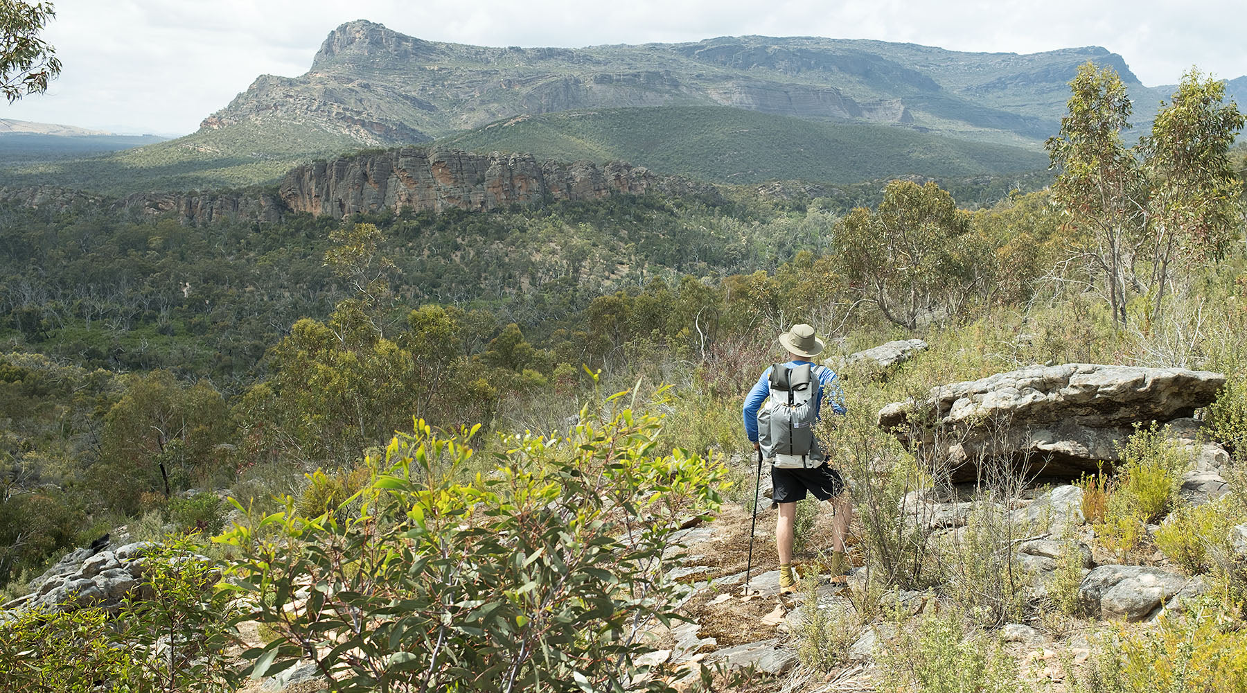 A hiker carrying a backpack, handmade by OrangeBrown in Australia, through the beautiful landscape along the Grampians Peaks Trail